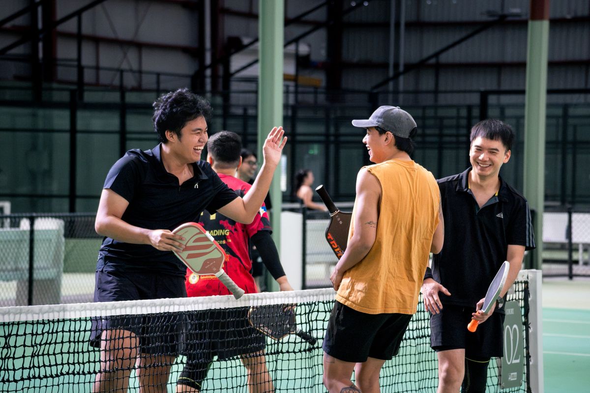 Kitchen Club players laughing and high-fiving at the net